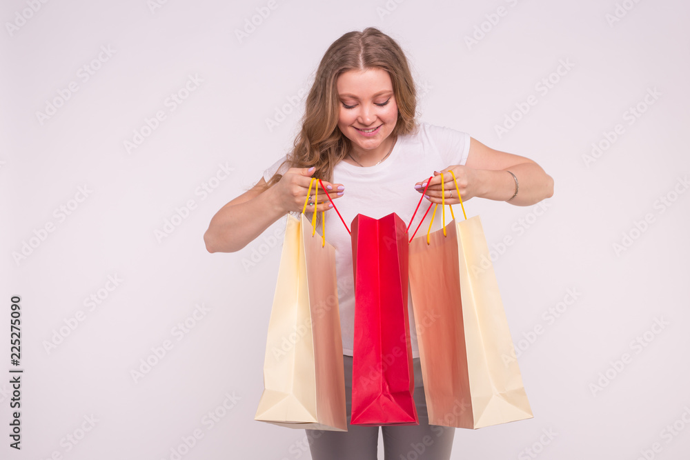 Young surprised blonde woman look into the shopping bag on white background