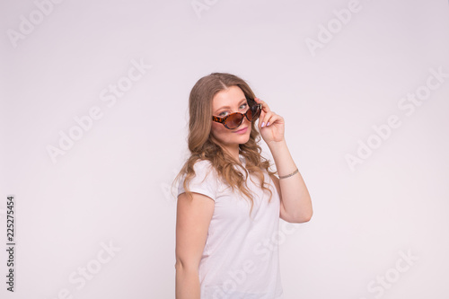 Beautiful white curly young woman wearing white t-shirt and sunglasses on white background with copy space