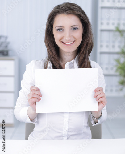 business woman showing blank sheet,sitting behind a Desk