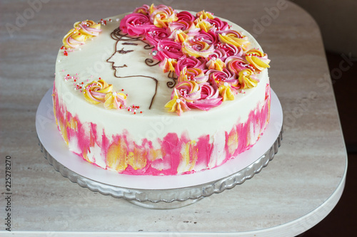 Festive cake with cream flowers and a girl face on a light background