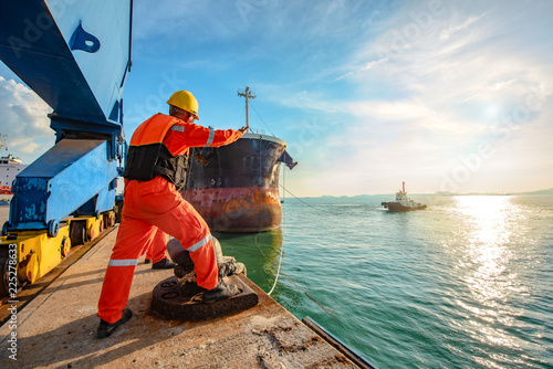 ship vessel is on leaving departure from the port terminal after completion of loading/discharging operation by gang of mooring attending at last party, tug boat standing by to safety assist towage