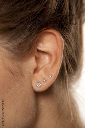 Photo Closeup of female ear with three earrings