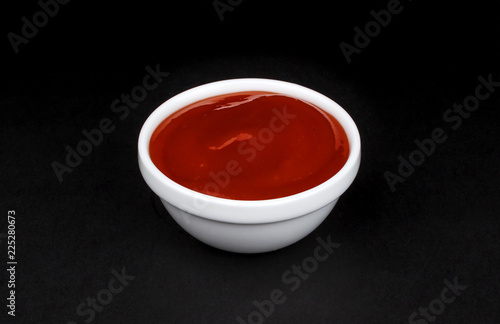 Ketchup in white bowl on black background