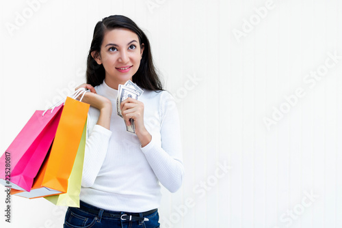 Beautiful attractive Asian female enjoy shopping online with full of bags on sale with happiness and joyful. Remaining more money in her hand for next shop. Studio shot on white background. 