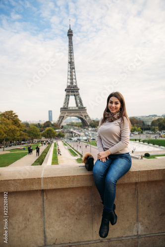 Beautiful lady sist on border against of eiffel tower. Lady smile and have fun photo