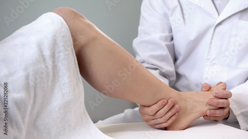 Traumatologist moving patient ankle, assessing severity of injury, closeup