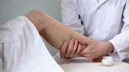 Rehabilitation specialist uses cream for leg massage, recovery after sprain