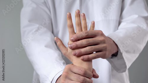 Billede på lærred Doctor moving patient wrist, first aid in clinic, assessing severity of injury