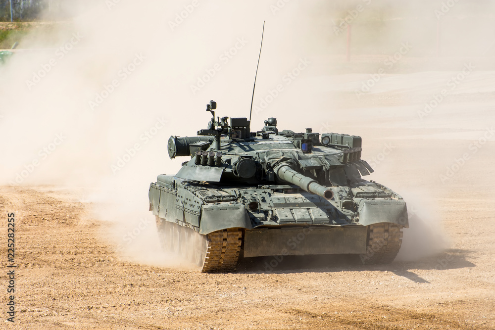 Powerful military tank rides at a high speed along the dusty field. Powerful military tank rides at a high speed along the dusty field.
