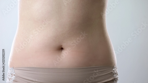 Young ladys flat belly closeup, healthy nutrition and beautiful slim body