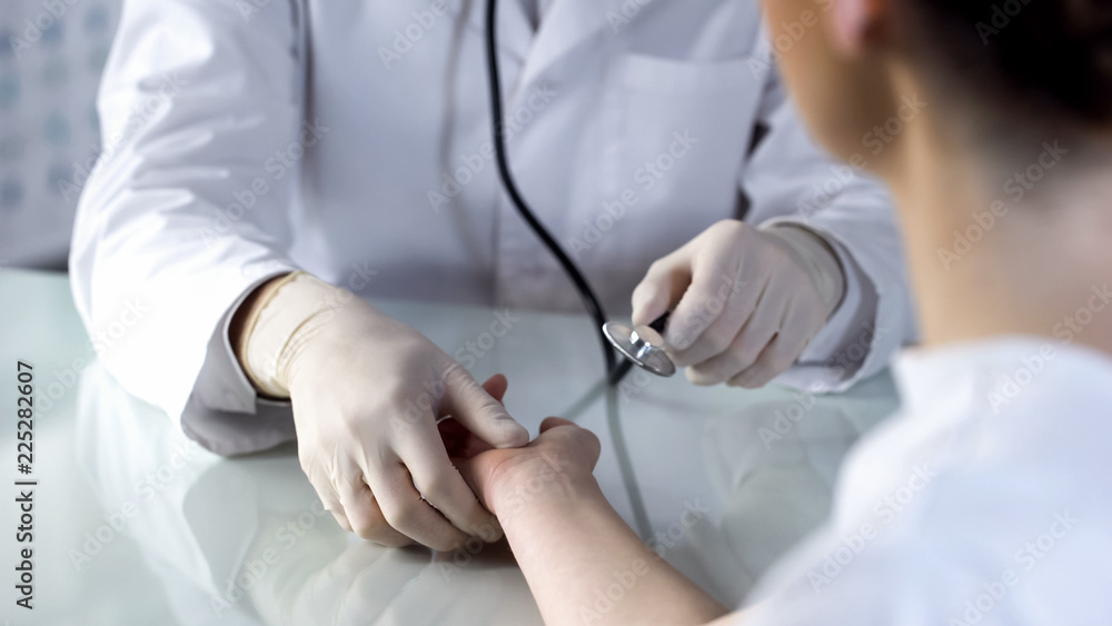 Therapist checking females pulse with stethoscope, appointment at clinic, health Therapist checking females pulse with stethoscope, appointment at clinic, health