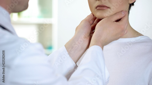 Male physician checking patient throat and neck, health examination in hospital photo