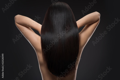 back view of woman with beautiful shiny hair isolated on black