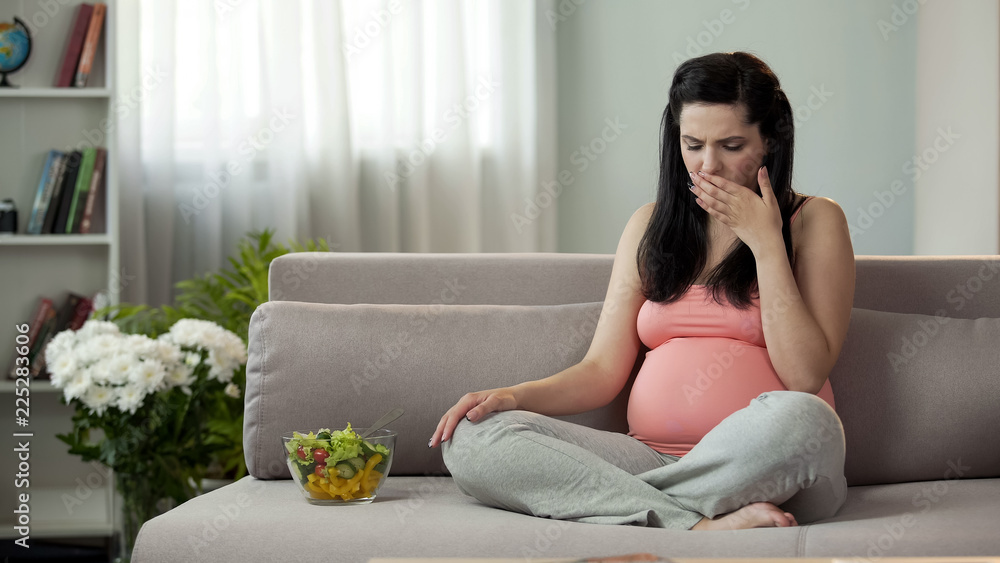 Pregnant girl suffering toxicosis, eating vegetable salad, feeling sickness Pregnant girl suffering toxicosis, eating vegetable salad, feeling sickness