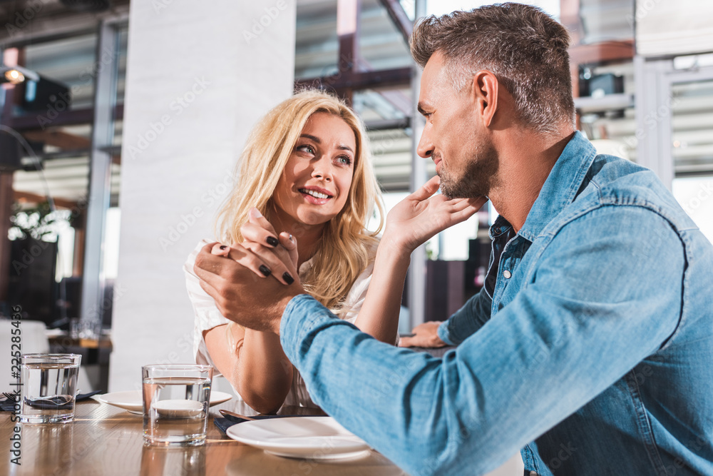 happy couple talking and looking at each other at table in cafe happy couple talking and looking at each other at table in cafe