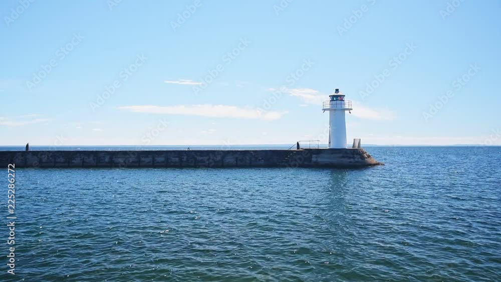Backlit lighthouse at the end of a stone pier in lake Vattern outside Hjo in Sweden. Backlit lighthouse at the end of a stone pier in lake Vattern outside Hjo in Sweden.