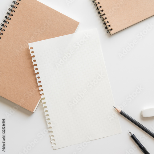 graph paper with spiral notebook, pencil and eraser on white background.