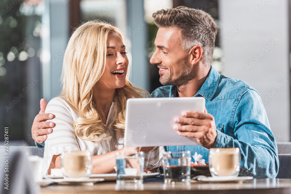 happy couple using tablet at table in cafe happy couple using tablet at table in cafe