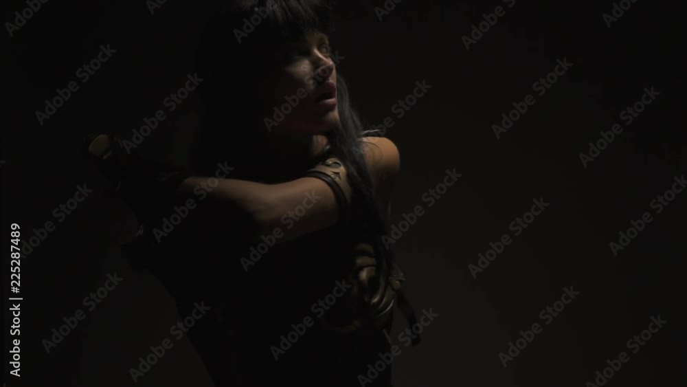 The long-haired Amazon pulls out a sword standing in the dark The long-haired Amazon pulls out a sword standing in the dark