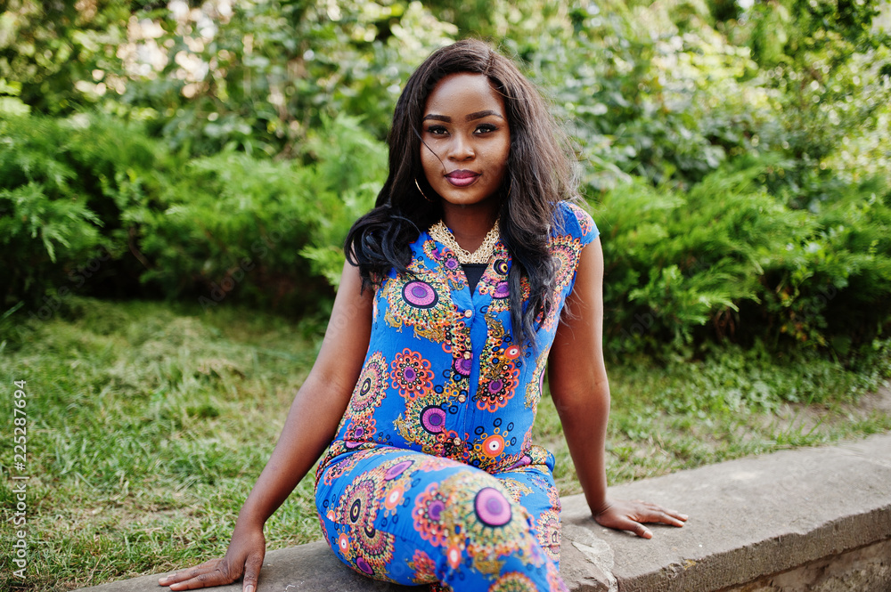 African american girl in coloured clothes sitting outdoor. Fashionable black woman. African american girl in coloured clothes sitting outdoor. Fashionable black woman.