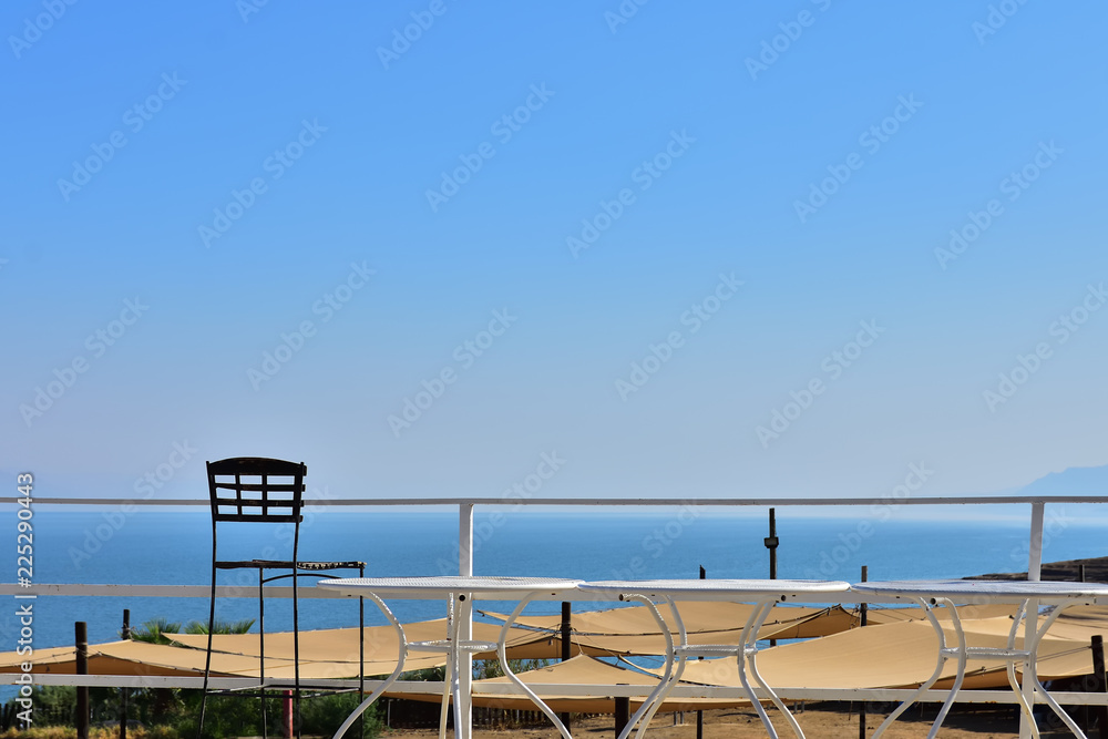 240 meters below sea level, the lowest place on the planet, view of the Dead Sea, fences, tables and chairs in the foreground, cloudless sky 240 meters below sea level, the lowest place on the planet, view of the Dead Sea, fences, tables and chairs in the foreground, cloudless sky