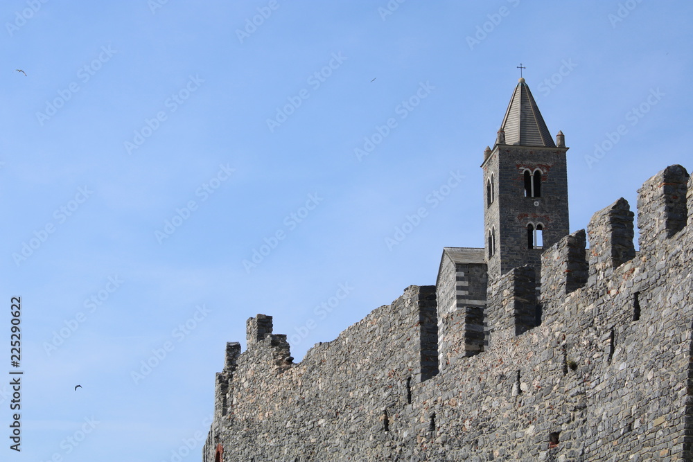 Mura medievale con campanile e uccelli in volo