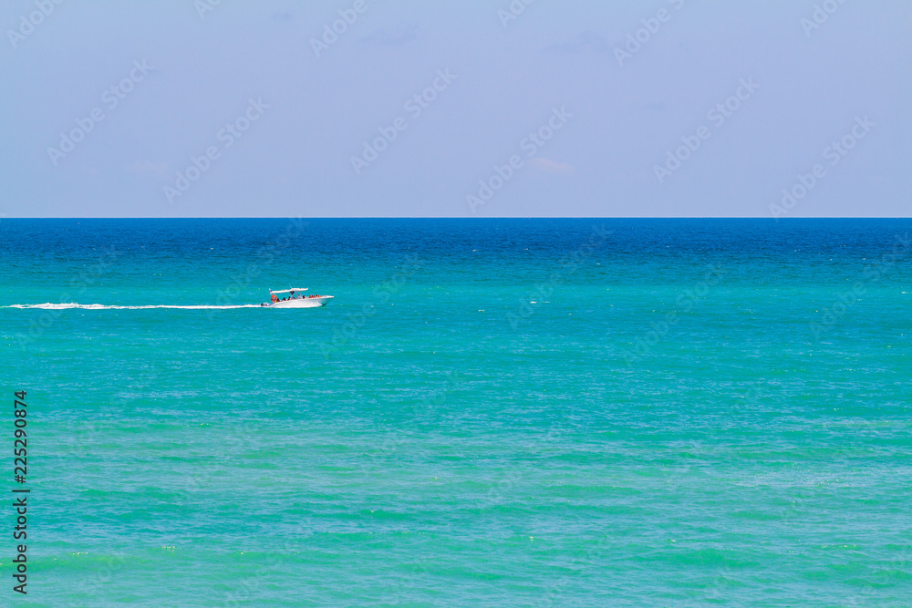 The smooth sea and the small boat with people. Clearly sky in sunshine day.