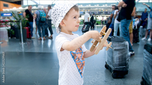 Portrait of 2 years old toddler boy playing with toy airplane in airport photo