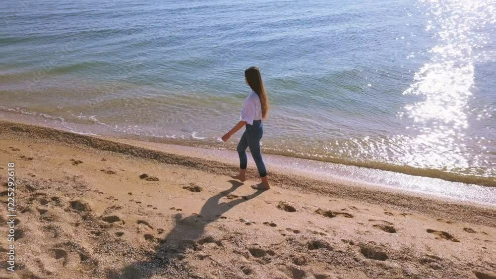 4K Aerial. Young girl teenager walk on ocean or sea beach. Lateral view, slow movement 4K Aerial. Young girl teenager walk on ocean or sea beach. Lateral view, slow movement