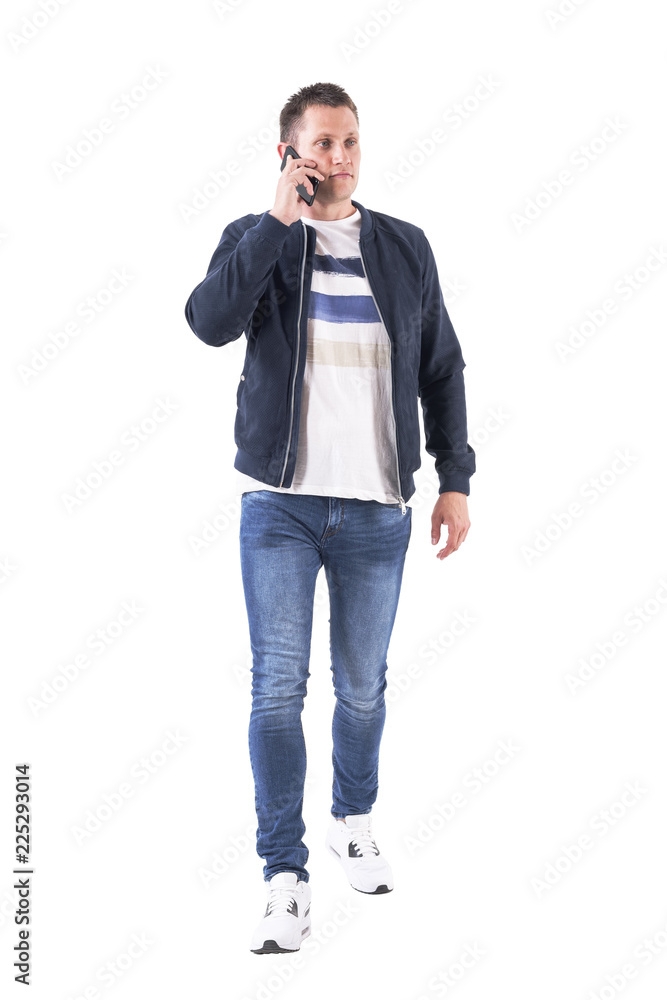 Front view of serious confident man talking on the phone walking towards camera and looking away. Full body isolated on white background. Front view of serious confident man talking on the phone walking towards camera and looking away. Full body isolated on white background.