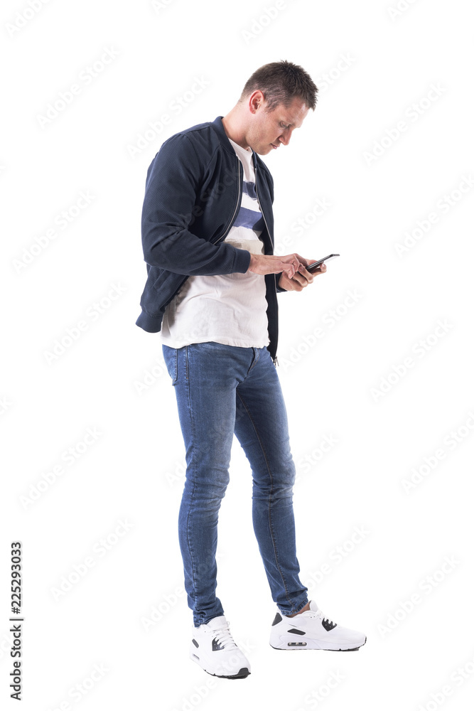 Side view of young casual man typing message on mobile phone. Full body isolated on white background. Side view of young casual man typing message on mobile phone. Full body isolated on white background.
