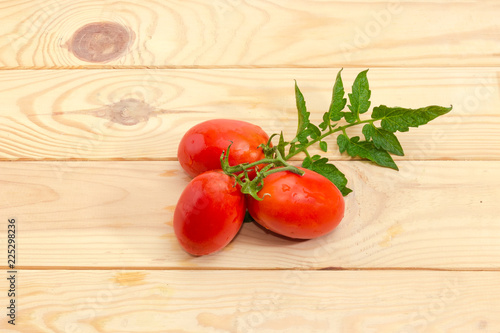 Branch of plum tomatoes with leaf on a wooden surface