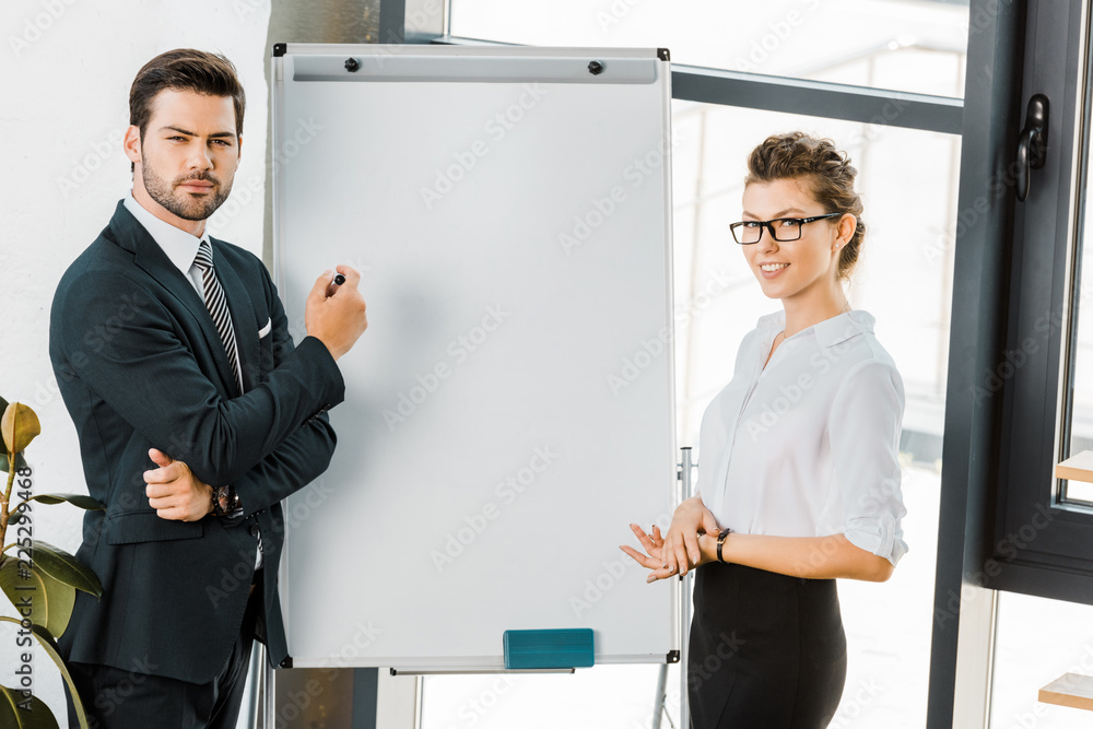 portrait of young business colleagues standing at empty white board in office