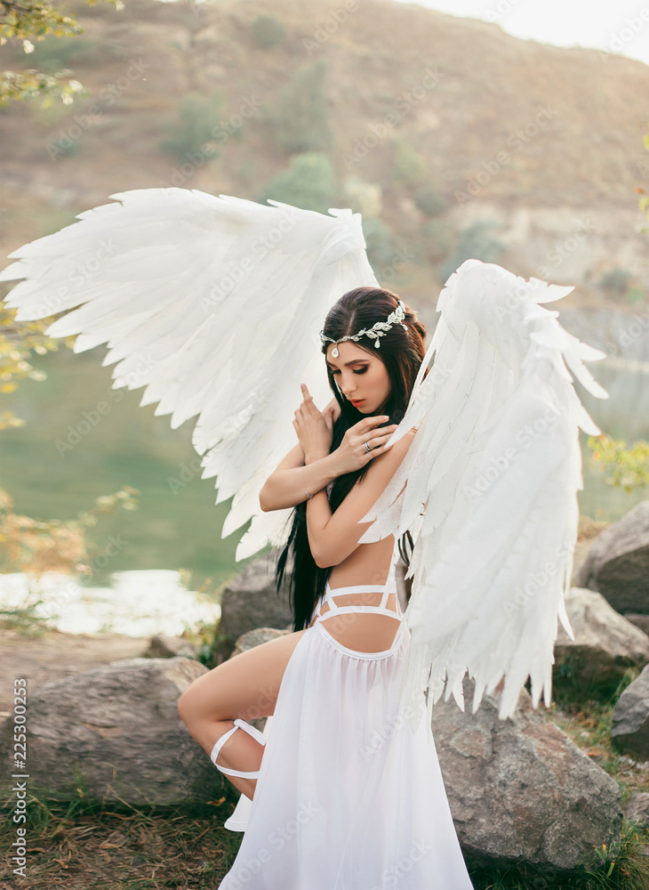 A heavenly angel in a fabulous, sexy dress with white wings, walks against  the backdrop of