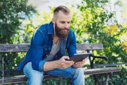 Young bearded man in jeans using a tablet pc
