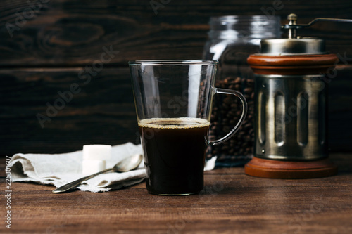 Coffee, black, in a transparent mug on a wooden background, hot drink