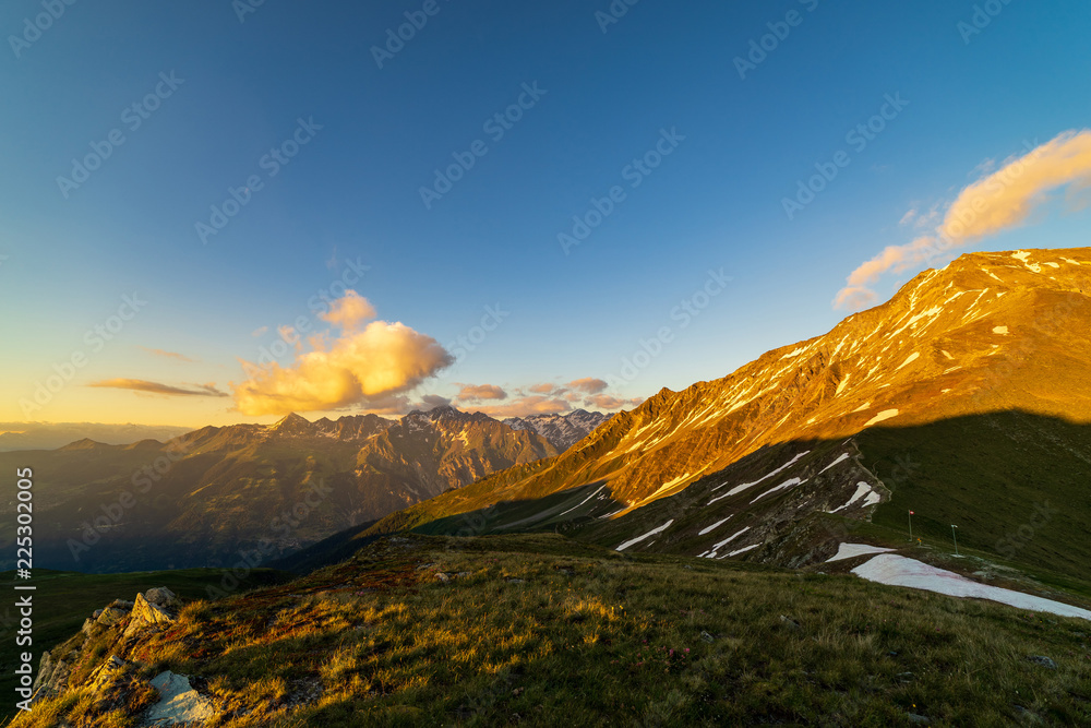 Obraz premium Dramatic sunset scene in high mountains. Clouds covering high peaks of Valais Alps (Pennine Alps), Switzerland in a evening light.