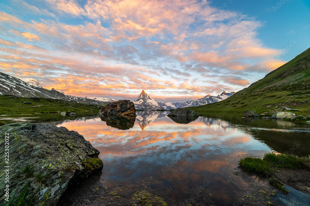 Obraz premium Morning shot of the golden Matterhorn (Monte Cervino, Mont Cervin) pyramid and blue Stellisee lake. Sunrise view of majestic mountain landscape.