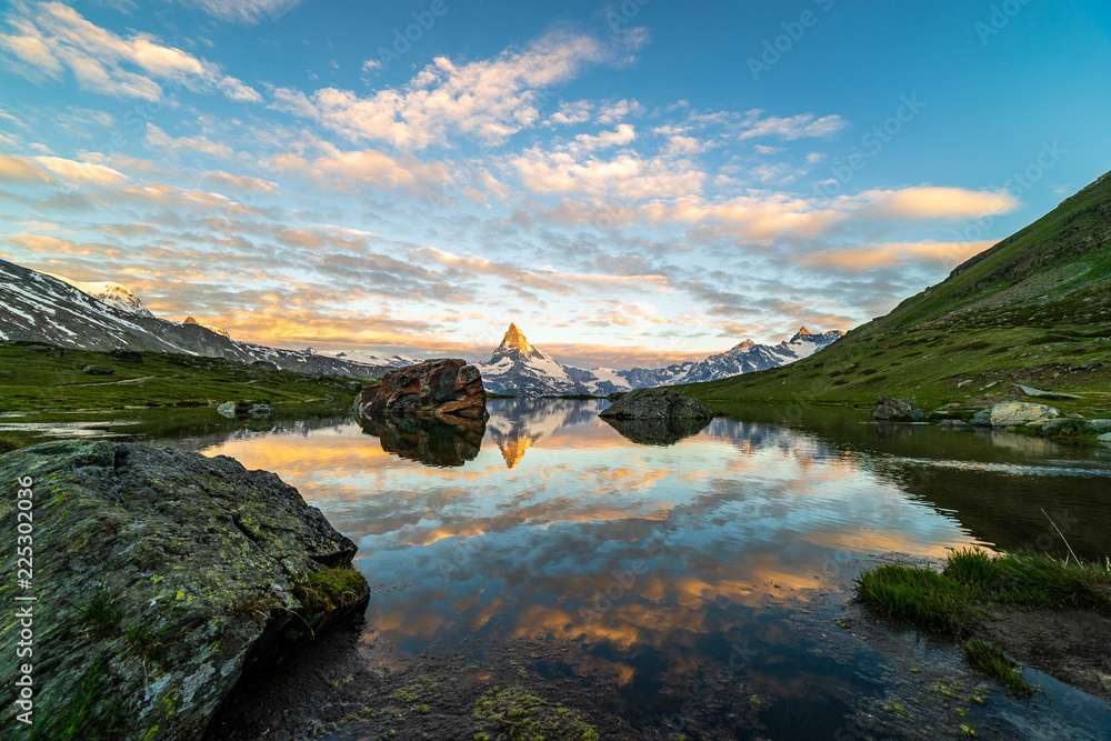 Obraz premium Morning shot of the golden Matterhorn (Monte Cervino, Mont Cervin) pyramid and blue Stellisee lake. Sunrise view of majestic mountain landscape.
