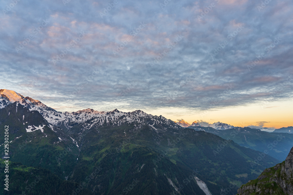 Scenic view of beautiful Swiss Alps mountains. Dramatic early morning scene in high mountains with first light. Blue hour sunrise with pink and blue tones, Switzerland.