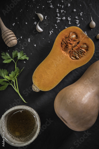 organic butternut squash with spices and ingredients for making on a black slate,