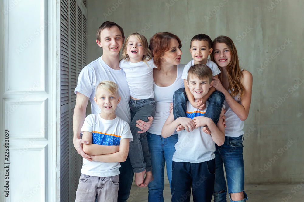 Φωτογραφία Happy family mother, father and five children near the wall at home