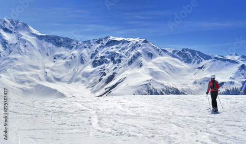 skier on a slope in alpine snowy mountain under blue sky