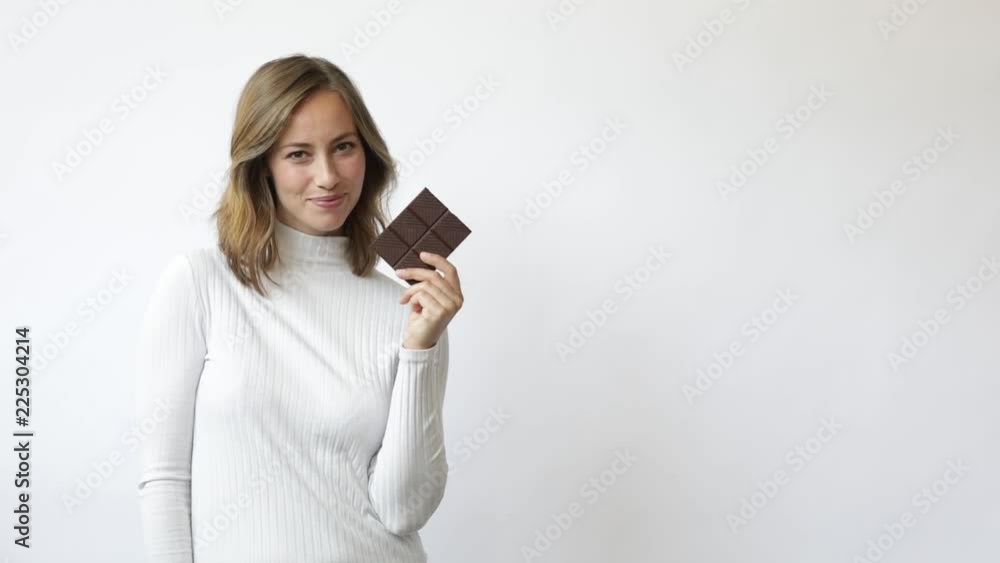 young woman on white background with chocolate smiling laughs tempted and considering slowmotion young woman on white background with chocolate smiling laughs tempted and considering slowmotion