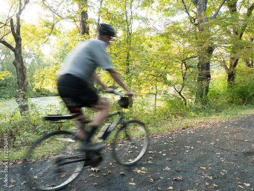 Motion Blur shot of a tall adult male riding a rails to trails bike on a path in Connecticut