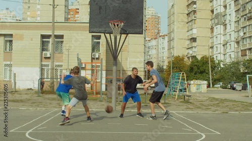 Offensive streetball team scoring field goal in the paint while playing basketball game on outdoor court. Baskteball player making successful assit to his teammate during streetball match ooutdoors. photo