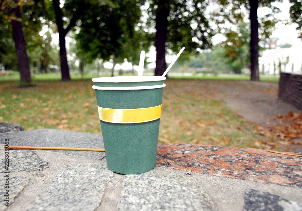 Green paper cup on the park path Green paper cup on the park path