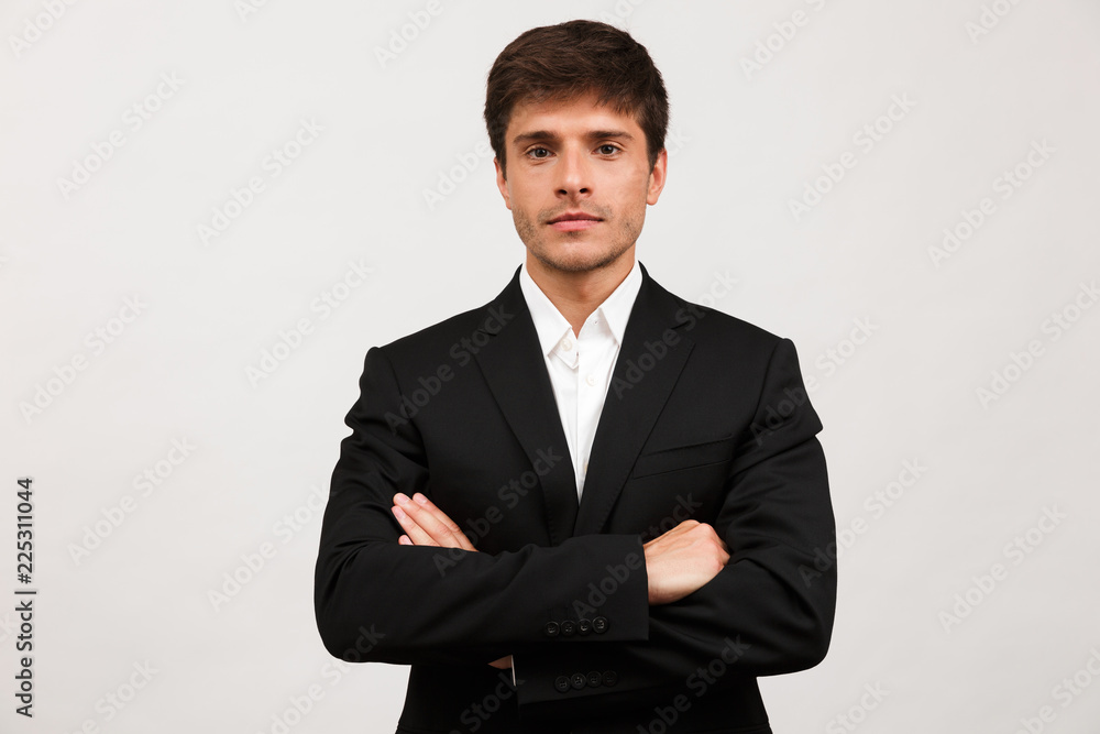Handsome serious young businessman standing isolated over white background wall. Handsome serious young businessman standing isolated over white background wall.