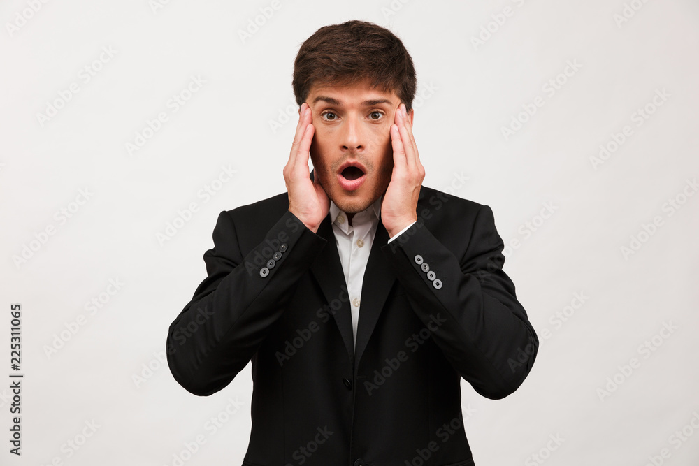 Shocked young businessman standing isolated over white background wall. Shocked young businessman standing isolated over white background wall.