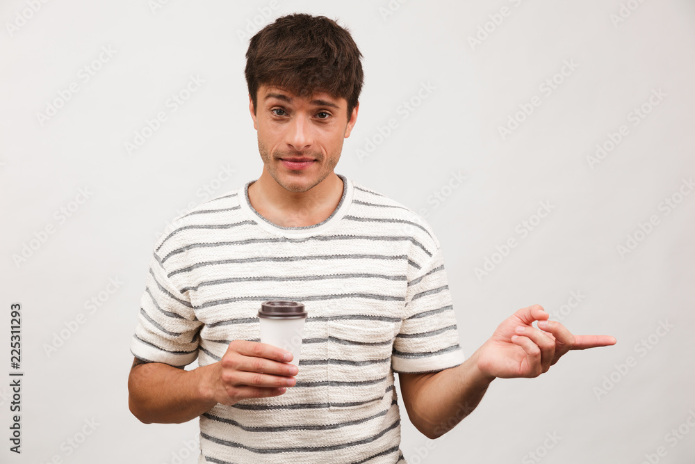 Cheerful handsome man standing isolated over white background wall drinking coffee pointing. Cheerful handsome man standing isolated over white background wall drinking coffee pointing.